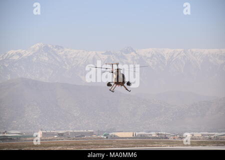 Un MD 530F guerriero Cayuse attacco leggero elicottero della Afghan Air Force sorvolano aeroporto militare di Kabul, Afghanistan, di fronte all'Hindu Kush mountain range all'orizzonte. Foto Stock