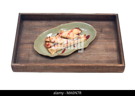 Delizioso formaggio blintz con sciroppo di lampone sulla piastra di verde e legno vassoio vintage isolati su sfondo bianco Foto Stock