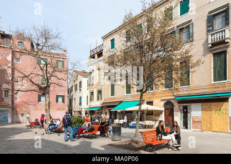 Campo Santa Maria Nova, Cannaregio, Venezia, Veneto, Italia con locale veneziani e turisti che si siedono sui banchi godendo il sole invernale Foto Stock