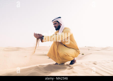 Uomo che indossa tradizionali vestiti degli emirati arabi uniti di  trascorrere del tempo nel deserto Foto stock - Alamy