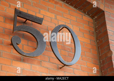 Numero 50 tagliato da acciaio su un muro di mattoni. Foto Stock