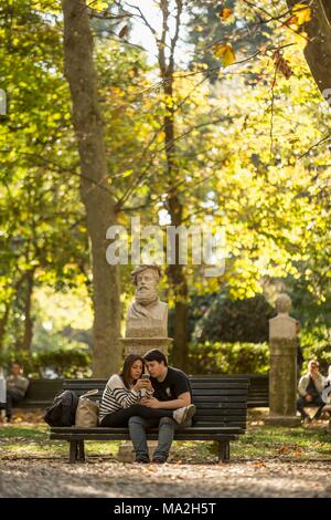 Un giovane su una panchina nel parco di Villa Borghese, Roma Foto Stock