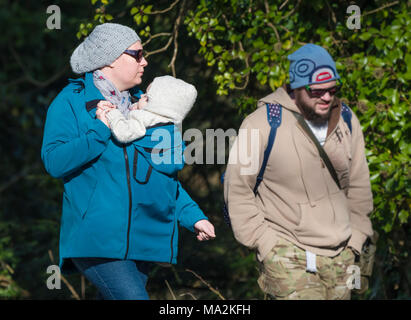 Un paio di passeggiate in inverno con la donna che porta un bambino in un supporto fissato alla sua parte anteriore. Tenere il bambino vicino. Foto Stock