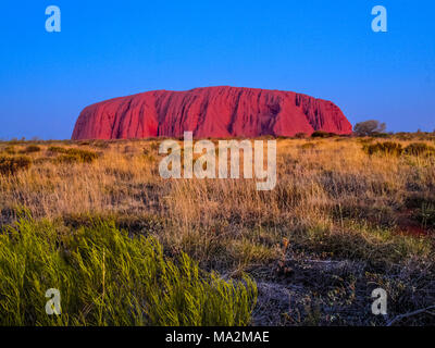 Tramonto a Ayers Rock. Australia. Uluru, o Ayers Rock, è un massiccio monolito di pietra arenaria nel cuore del nord del territorio arido 'Red Centre'. Th Foto Stock