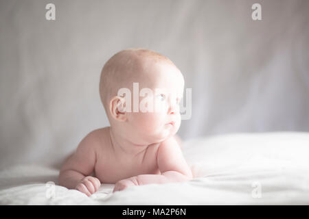 Molto carino baby boy guardando verso la luce con espressione contemplativa Foto Stock