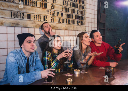 La vittoria del gruppo di giovani amici bello guardare la TV e fare il tifo per la loro squadra durante il riposo nel pub. Fai il tifo per la tua squadra Foto Stock