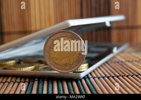 Pila di monete in euro di specchio riflettere wallet giace su legno di bambù sfondo tabella di denominazione è di 2 euro - Lato posteriore Foto Stock