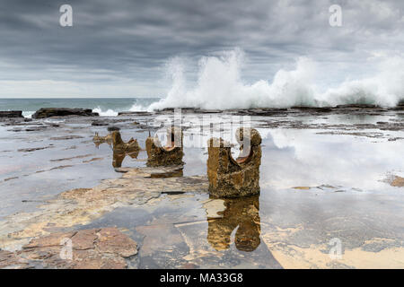 Onde che si infrangono su un ripiano di roccia a Coledale spiaggia vicino Sydnet Foto Stock