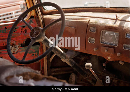 L'interno di un vecchio arrugginito, veicolo di antiquariato che mostra il volante e sul cruscotto. Foto Stock