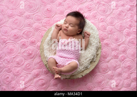 Ritratto di un sonno, un mese bambina indossa un uncinetto, rosa romper. Foto Stock