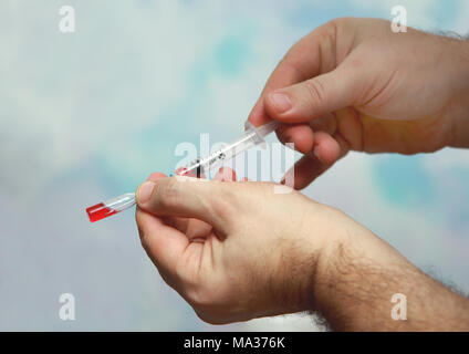 Persone guadagnando in una siringa farmaco rosso. Foto Stock