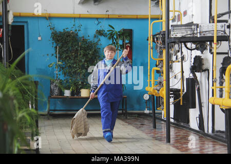 Vecchia donna il detergente in abbigliamento da lavoro sul sito di fabbricazione Foto Stock