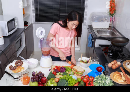 Giovane donna frullati con Blender in cucina Foto Stock