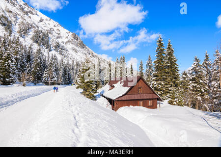 Coppia di turisti sulla strada innevata e casa di montagna vicino alla strada di Morskie Oko lago nella stagione invernale, Monti Tatra Foto Stock