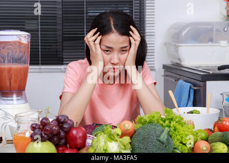 Premuto giovane donna cucinare in camera con cucina Foto Stock