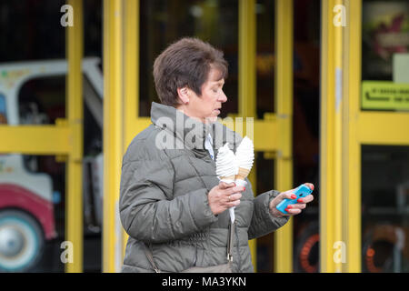 Buone Vacanze Venerdì, Blackpool, Lancashire. Il 30 marzo 2018. Regno Unito Meteo. Una donna è determinata a fare la maggior parte dei poveri la molla condizioni atmosferiche come ella gode di un gelato nella città balneare di Blackpool in Lancashire. Credito: Cernan Elias/Alamy Live News Foto Stock