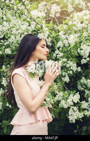 Perfetto giovane donna odore di fiore in fiore fiori di primavera sullo sfondo del giardino Foto Stock