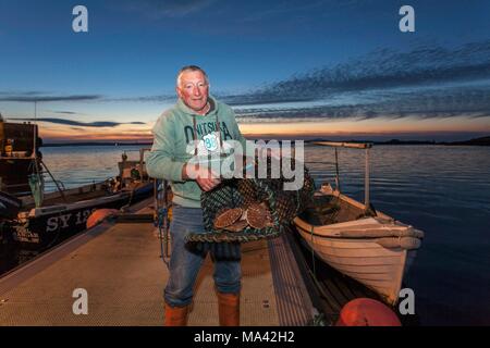Il Fisher Murdo MacAuley con capesante in porto Leverburgh sull isola di Harris in Scozia Foto Stock