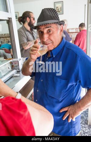 Un uomo di bere un piccolo bicchiere di vino al mercato delle pulci di Rastro a Madrid, Spagna Foto Stock