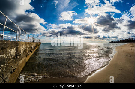 Scena di paesaggio di Pier, sul lago e sulla spiaggia di inizio primavera su di una bella giornata di sole con splendido cielo blu e nuvole bianche Foto Stock