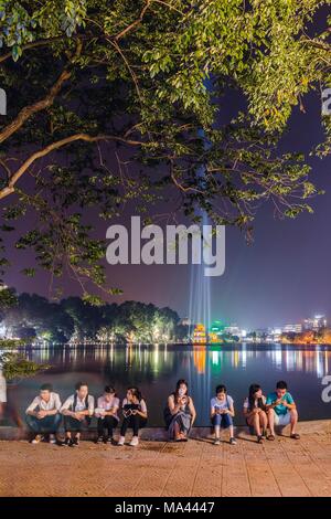 I giovani seduti accanto al lago Hoan Kiem ad Hanoi, Vietnam Foto Stock