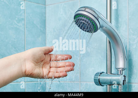 Un palmo di mano sotto getti di acqua in uscita dalla doccia a telefono con la barra di scorrimento. Foto Stock
