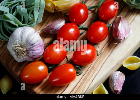 Chiudere fino a chiaroscuro cibo scuro ingredienti per la pasta con gli spaghetti, tagliatelle e penne tricolore e aglio Foto Stock