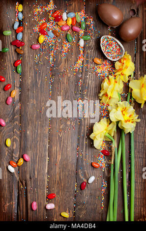 Pasqua sfondo vuoto con la Pasqua uova di cioccolato, caramelle e fiori di primavera. Vista da sopra con copia spazio. Foto Stock