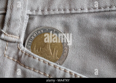 Moneta thailandese con una denominazione di 10 baht nel vecchio pocket di beige jeans denim Foto Stock