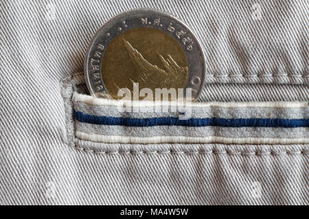 Moneta thailandese con una denominazione di 10 baht nella tasca di beige jeans denim con striscia blu Foto Stock