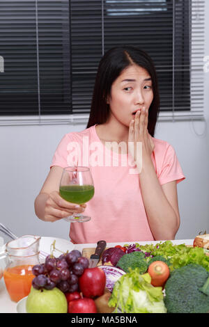 Infelice giovane donna di bere succo di verdura in cucina Foto Stock