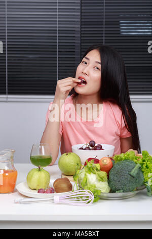 Giovane donna di mangiare uva in camera con cucina Foto Stock