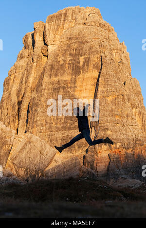 Un escursionista salta in fornt di Cinque Torri, Dolomiti, Cortina d'Ampezzo, provincia di Belluno, Veneto, Italia Foto Stock