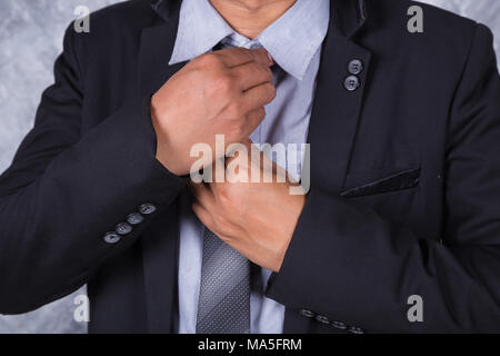 Close up business man in un vestito che fissa il suo tirante Foto Stock