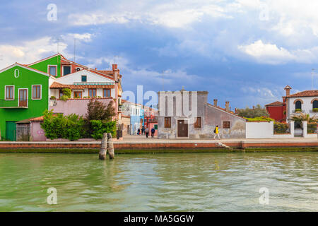 Una persona che cammina lungo un canale di Burano dopo la tempesta. Burano, Venezia, Veneto, Italia. Foto Stock