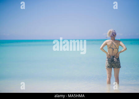 Bianco giovane ragazza capelli fissando all'oceano profondo in aruba guardando al mare turchese Foto Stock