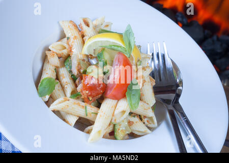 Una ciotola di Penne insalata di pasta, insalata di pasta di Penne. guarnita wirh fresco cuneo di limone e foglie di basilico fresco Foto Stock