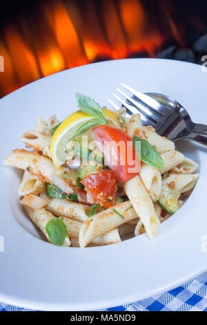 Una ciotola di Penne insalata di pasta, insalata di pasta di Penne. guarnita wirh fresco cuneo di limone e foglie di basilico fresco Foto Stock