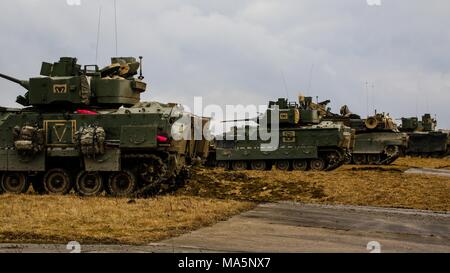 Una linea di M2 Bradley veicoli da combattimento e una M1 Abrams serbatoio, dal 5° Stormo, 4° reggimento di cavalleria, 2° Brigata corazzate contro la squadra, 1a divisione di fanteria, eseguire la scansione dell'area formazione per gli obiettivi da raggiungere durante un combinato di armi fuoco vivo esercizio (CALFEX) a Grafenwoehr Area Formazione, Germania, Mar 28, 2018. (U.S. Esercito foto di Spc. Hubert D. Delany III / 22nd Mobile degli affari pubblici distacco) Foto Stock