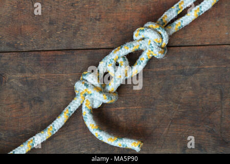 Due funi vincolato con nodi giacenti su sfondo di legno Foto Stock