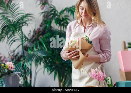 Foto di fiorista bouquet rende sullo sfondo di piante da interni in camera Foto Stock