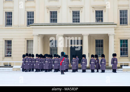 Irlandese guardie dal Queens reggimenti di guardia la preparazione per la cerimonia del Cambio della Guardia con un sopralluogo nella neve alla caserma di Wellington Foto Stock
