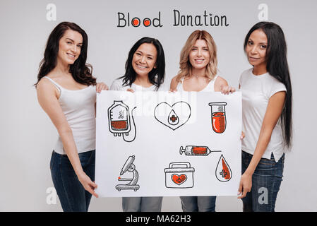 Le donne positive che coinvolgono le persone nella donazione di sangue e sorridente Foto Stock