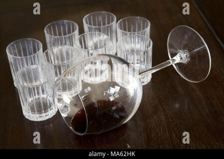 Cristallo ribaltata wineglass con resti di vino all'interno vicino al liquore bicchieri Foto Stock