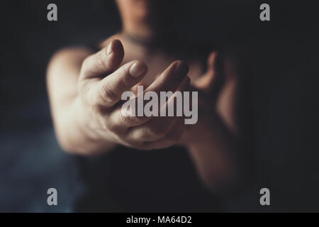 Donna di raggiungere con la sua mano verso qualcuno dal buio, invitando, premuroso gesto Foto Stock