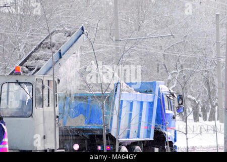 Vista anteriore del servizio spazzaneve carrello gritter e spandimento di sale sulla superficie della strada per impedire la formazione di ghiaccio nella neve tempestoso giorno d'inverno Foto Stock