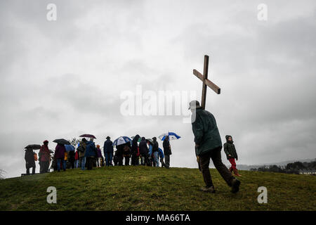 Una croce di legno è portato fino Roundhill in bagno, Wiltshire, dove molti cristiani della Chiesa le congregazioni prendere parte nel cammino di testimonianza di imitare il cammino che Gesù ha preso portando la sua croce attraverso le strade di Gerusalemme nel giorno di Venerdì Santo. Foto Stock