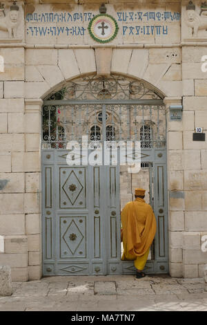 Un monaco etiope che entra attraverso la porta del composto di Debre Genet monastero (Santuario del paradiso) in cui la Chiesa etiopica di Kidane Mehret è situato in Etiopia Street West Jerusalem Israel Foto Stock