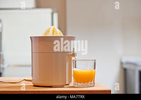 Spremiagrumi elettrico e succosa di vetro in una cucina moderna Foto Stock