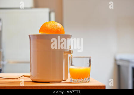 Spremiagrumi elettrico e succosa di vetro in una cucina moderna Foto Stock
